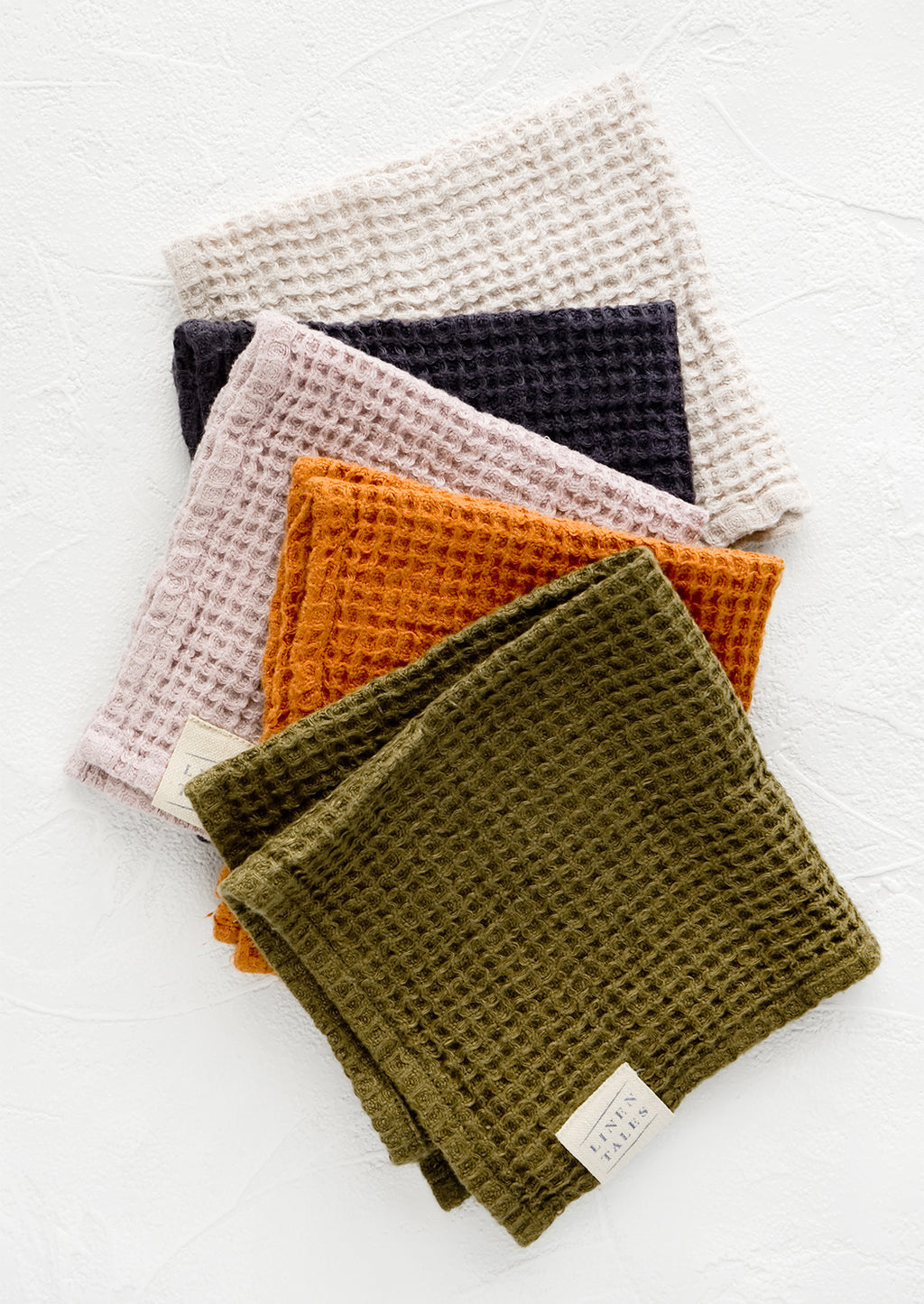 1: A row of folded waffle-weave linen washcloths, in an assortment of color options.