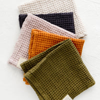 1: A row of folded waffle-weave linen washcloths, in an assortment of color options.