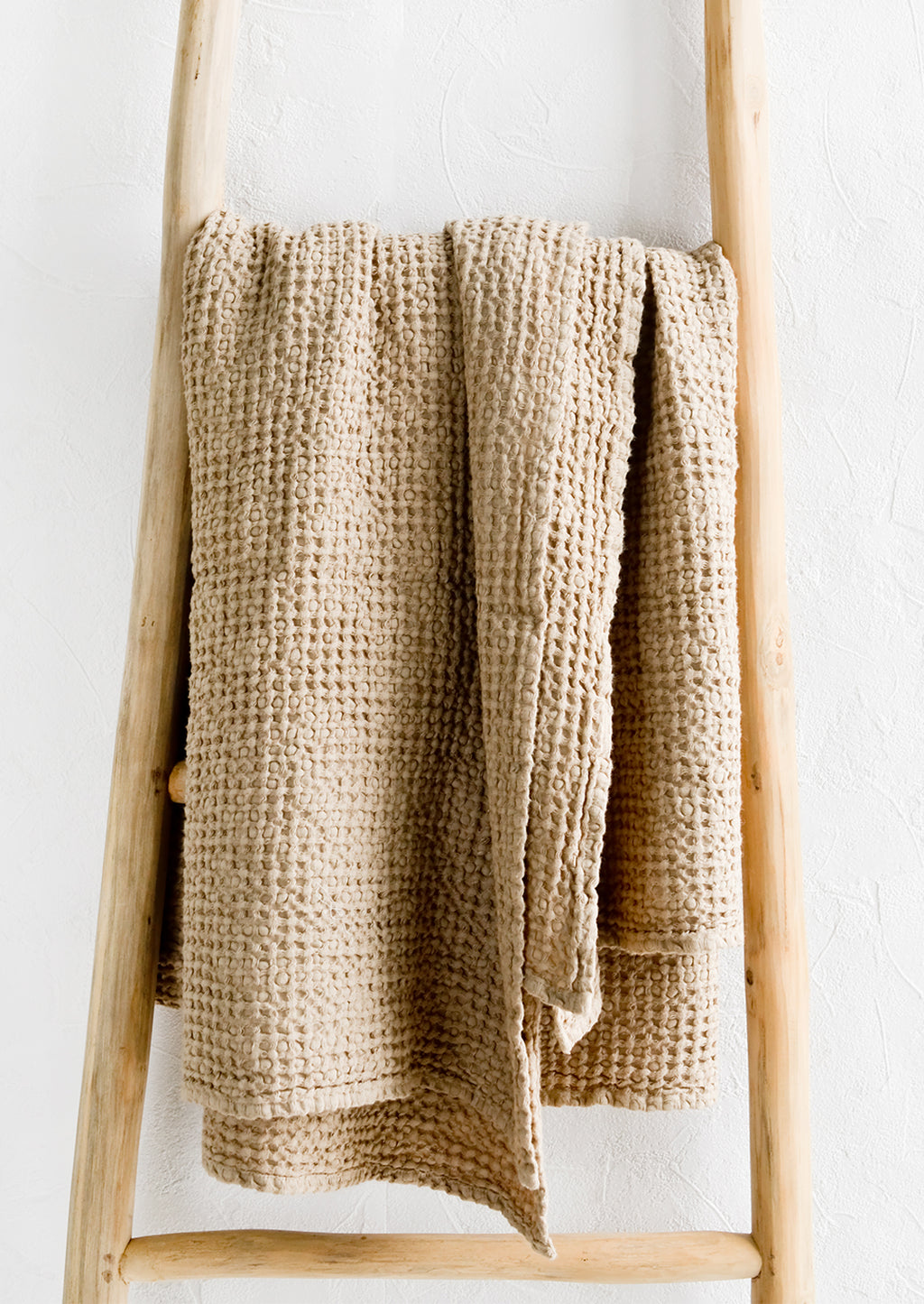 Beige / Full: A waffled throw in beige folded over a display ladder.
