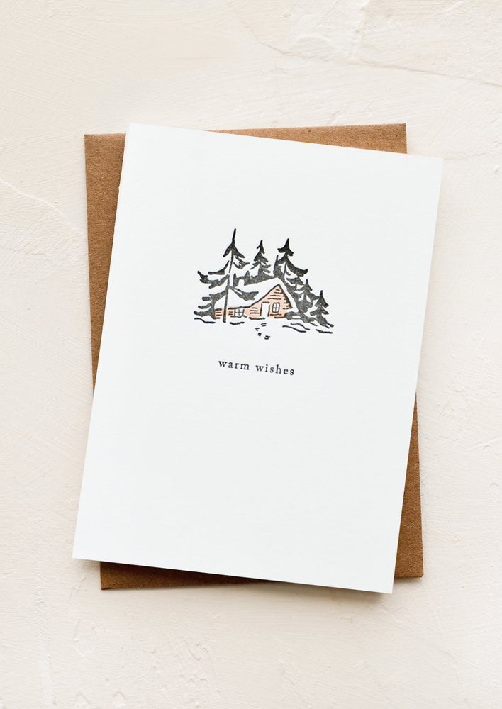 1: A letterpress printed greeting card with an image of a cabin in the words, text below image reads "warm wishes"