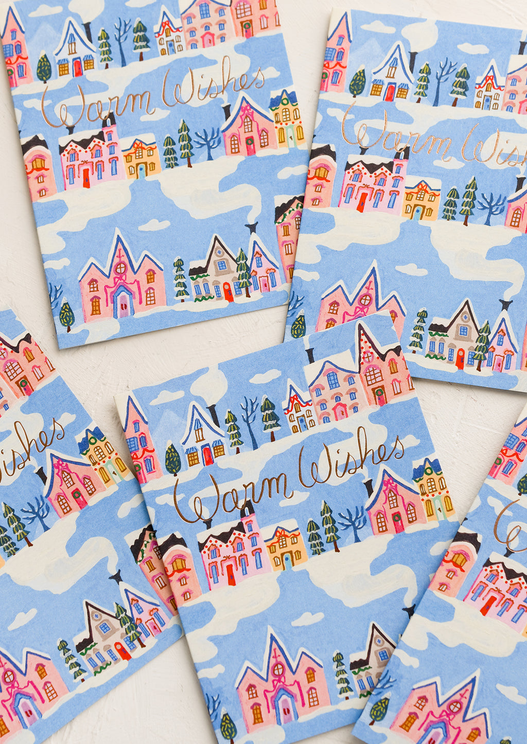 1: Greeting card with blue background and repeating rows of houses and trees. "Warm Wishes" written in copper script.
