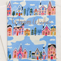 2: Greeting card with blue background and repeating rows of houses and trees. "Warm Wishes" written in copper script.