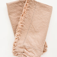 Cocoa: Two folded tan Cotton Napkins with frayed edges .