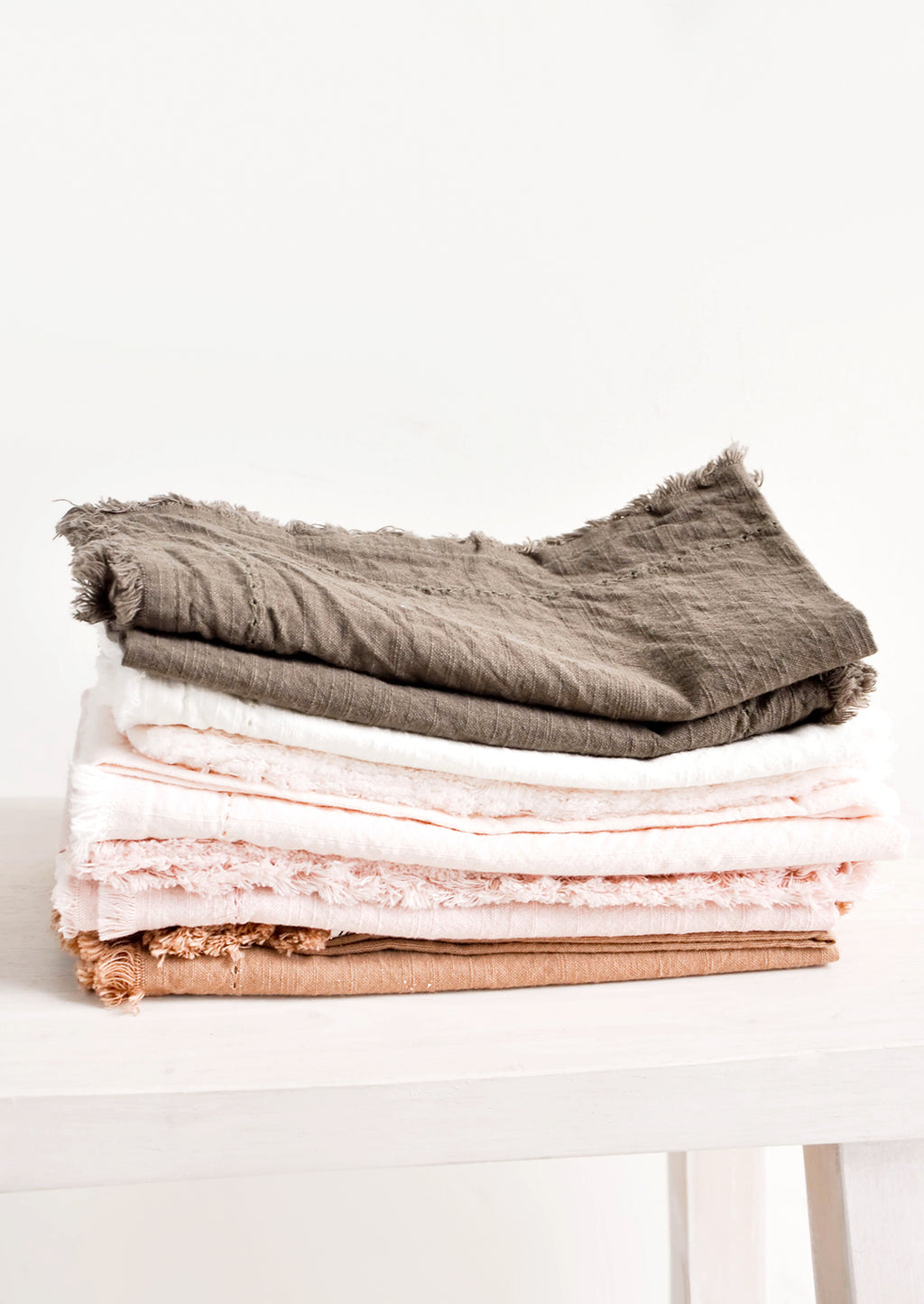 1: Stack of Cotton Napkins with frayed edges in browns and pinks.