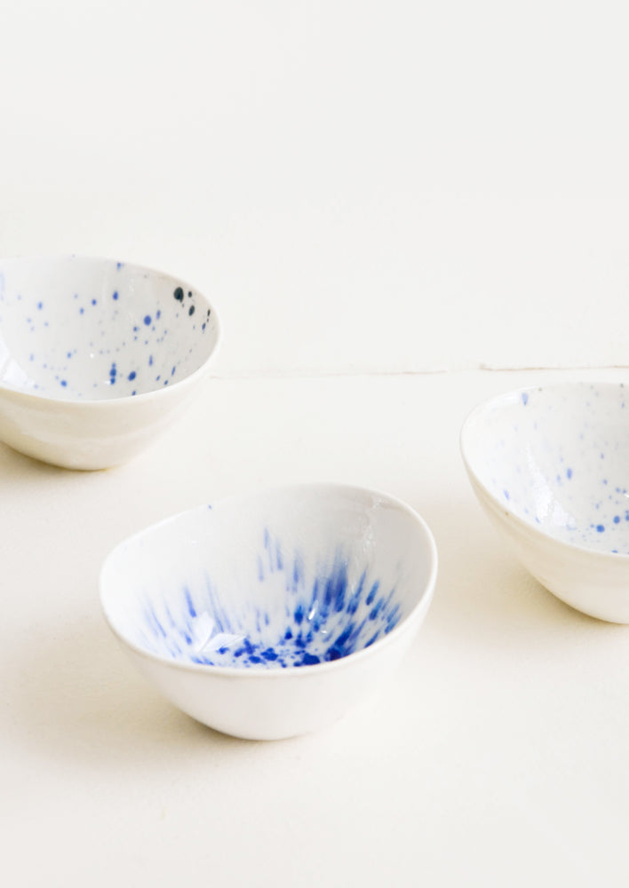 Small, oblong shaped ceramic bowls in white with randomized watercolor splatter pattern in blue