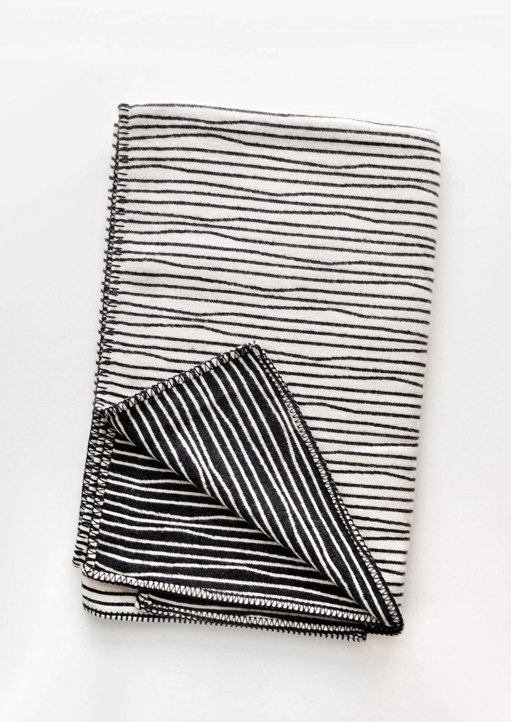 Ivory / Charcoal: Plush throw blanket with allover wavy lines print in black on white