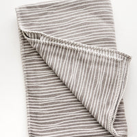 Taupe / Ivory: Plush throw blanket with allover wavy lines print in white on taupe