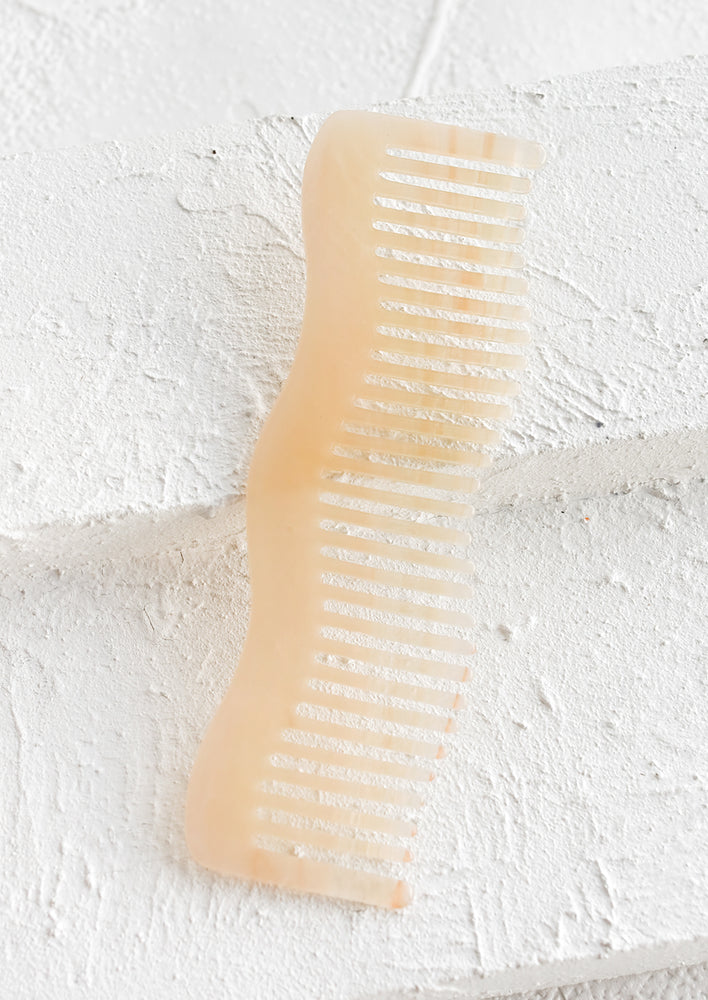 A wavy shaped acetate comb in peach.