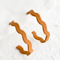 Caramel: A pair of hoop earrings in matte caramel with wavy shape.