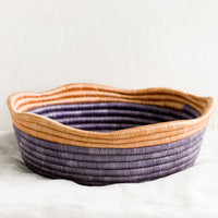 1: A purple woven shallow, round bowl with wavy peach rim at top.
