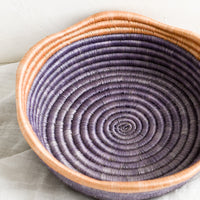 2: A purple woven shallow, round bowl with wavy peach rim at top.
