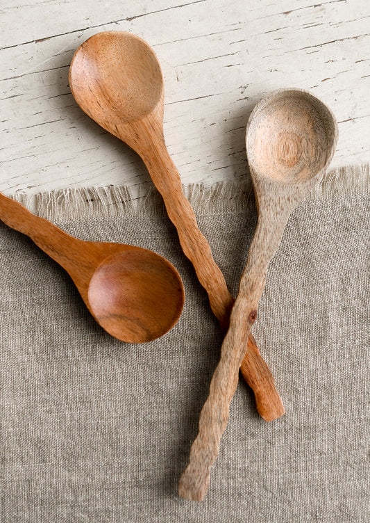 Three wooden spoons with wavy handles in various wood tones.