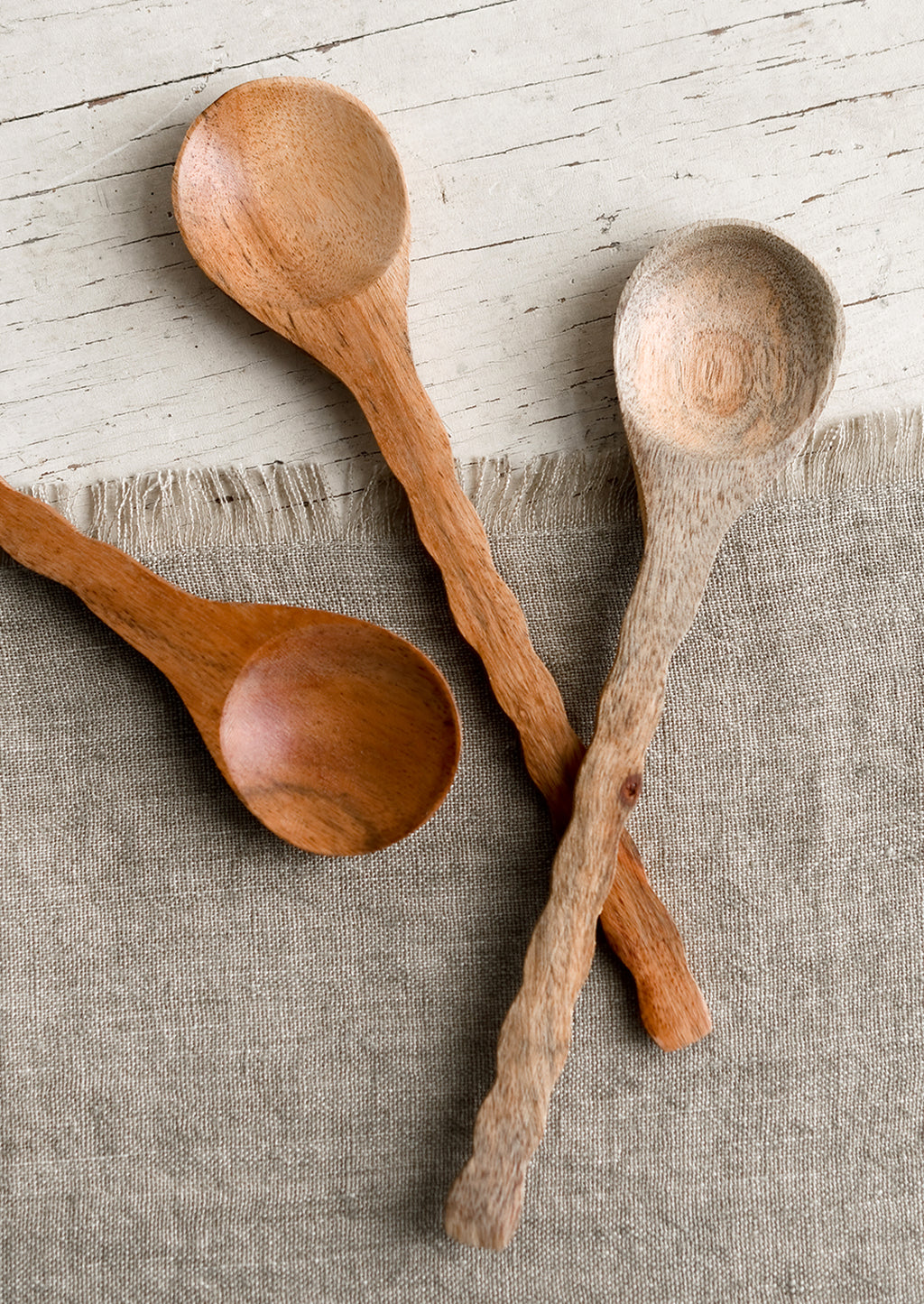 1: Three wooden spoons with wavy handles in various wood tones.