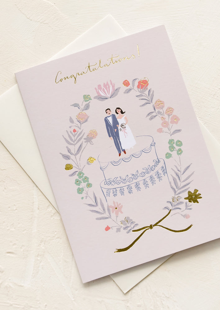 1: A greeting card with illustration of man and woman on top of a wedding cake.