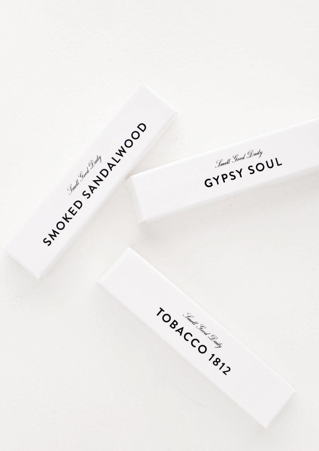 2: Three small glossy white cardboard packages with minimalist black text.