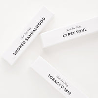 2: Three small glossy white cardboard packages with minimalist black text.