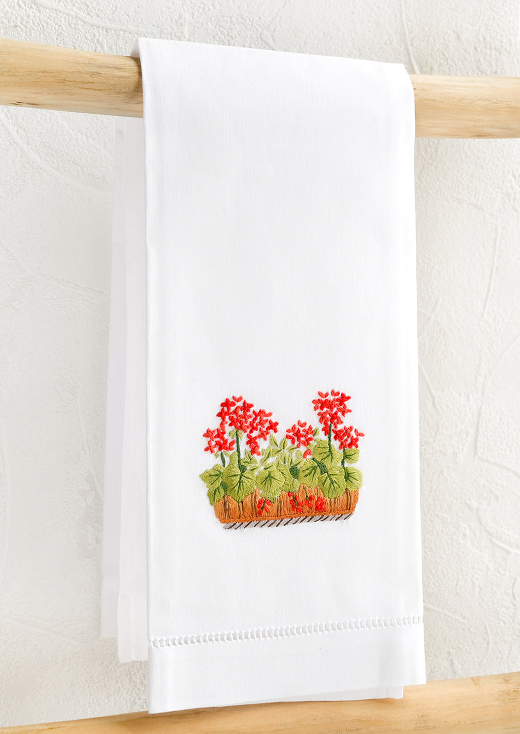 Geraniums: A white folded cotton hand towel with embroidered geranium design.