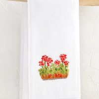 Geraniums: A white folded cotton hand towel with embroidered geranium design.