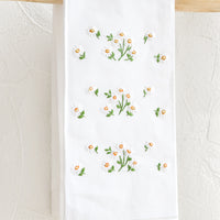 Scattered Daisies: A white folded cotton hand towel with embroidered floral design.
