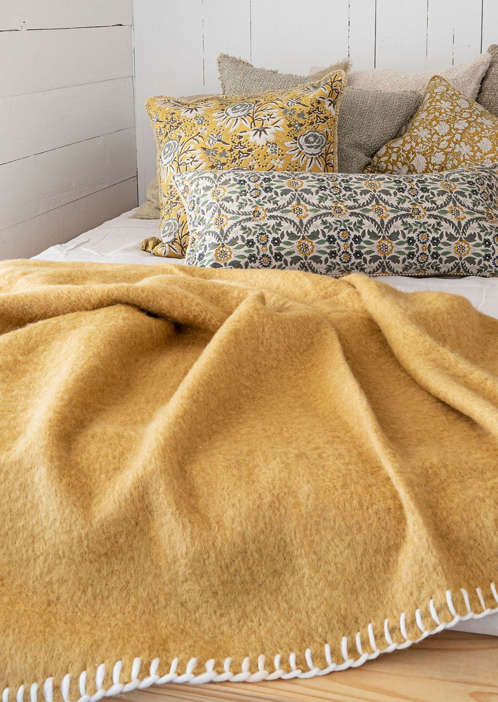 4: A mustard throw on a bed with throw pillows.