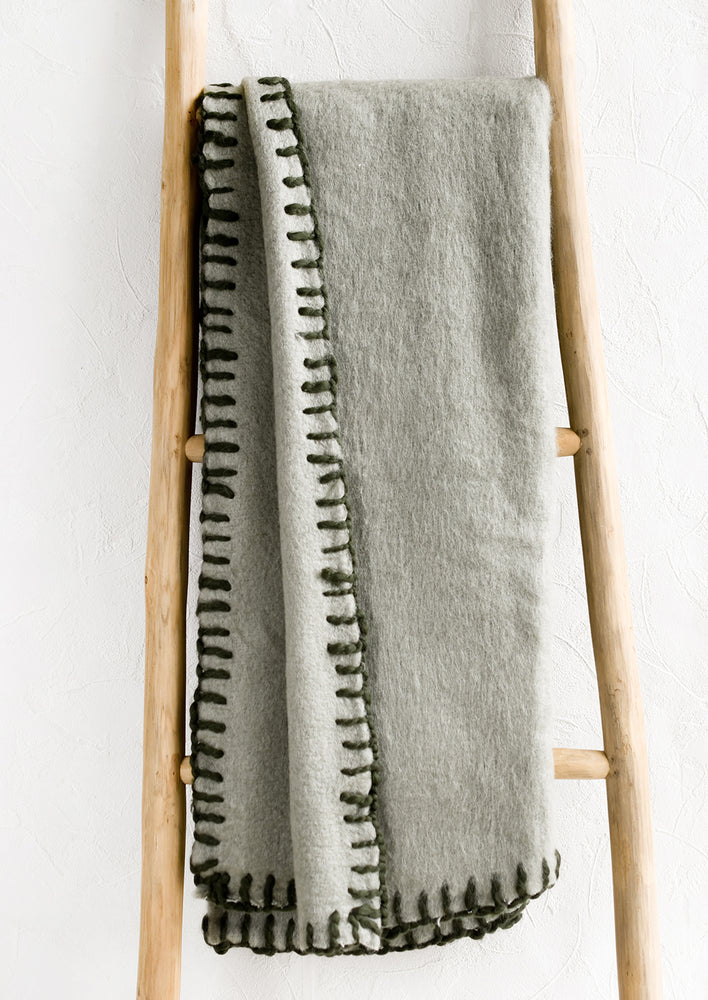 A sage mohair blanket with olive yarn whipstitched trim.