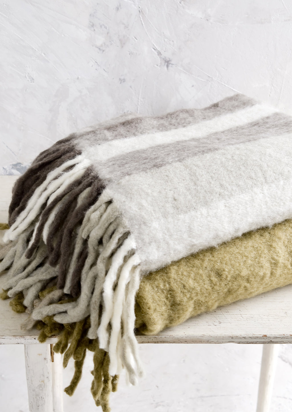3: Two fuzzy throw blankets, stacked on a table.