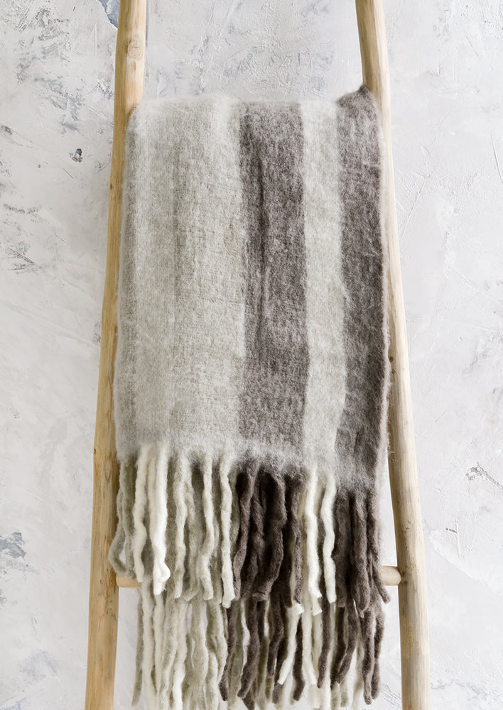 Fog Multi: A fuzzy throw blanket with exaggerated fringe in grey multi.
