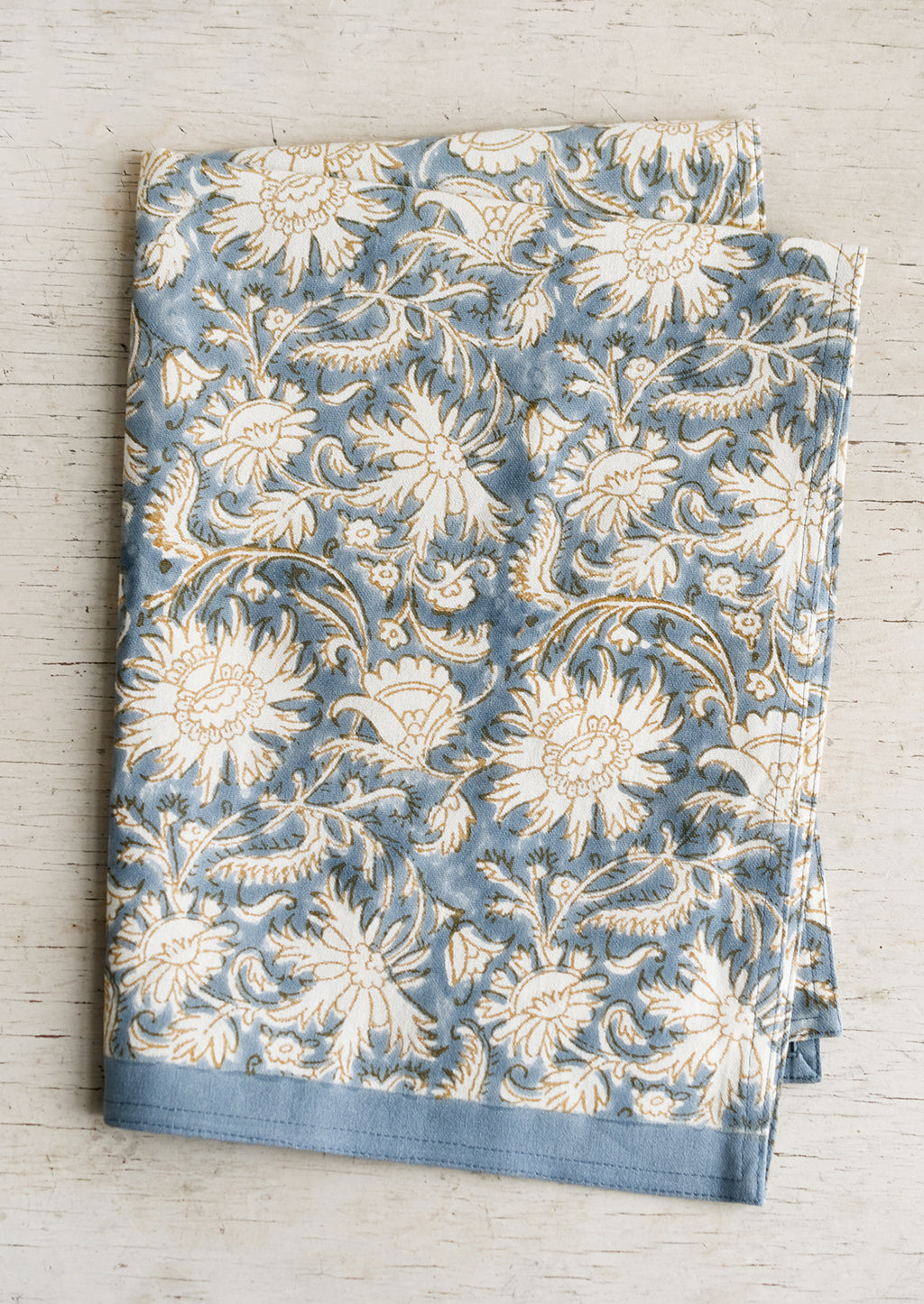 1: A block printed tea towel with floral pattern in blue, white and tan.