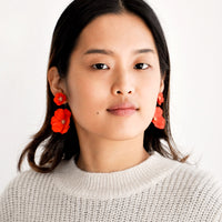 5: Model wears poppy red flower earrings and gray sweater.