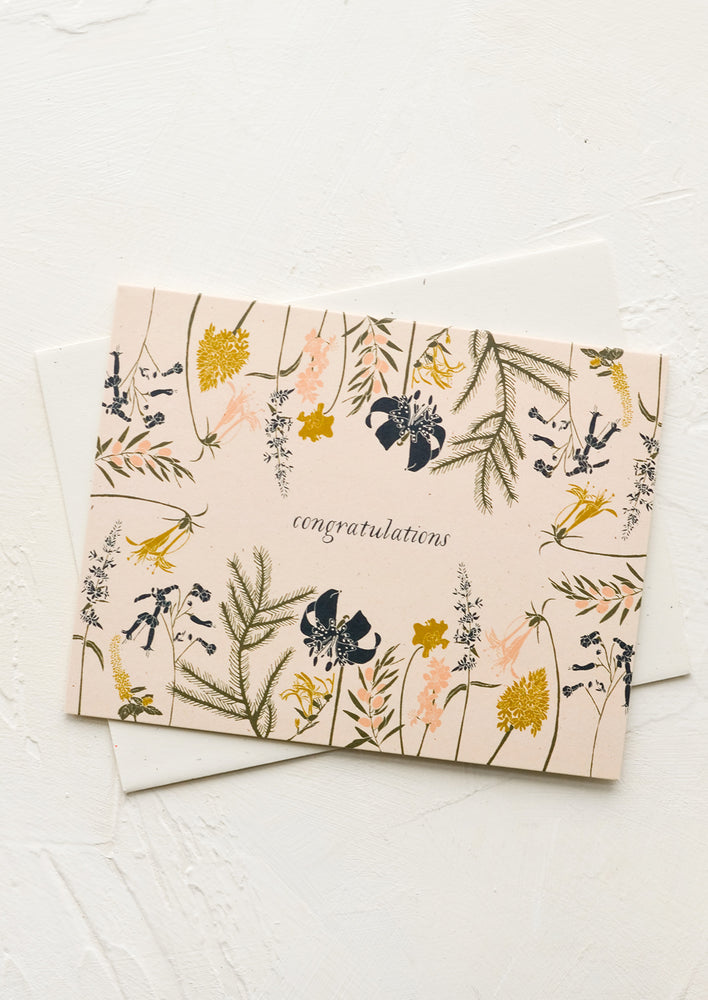A greeting card with blush background and wildflowers around "Congratulations" text at middle.