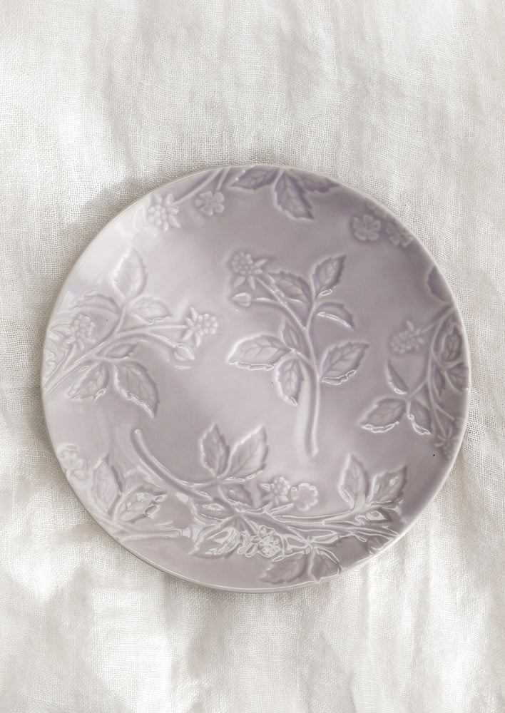 A round ceramic dessert plate in lavender with tonal raspberry pattern.