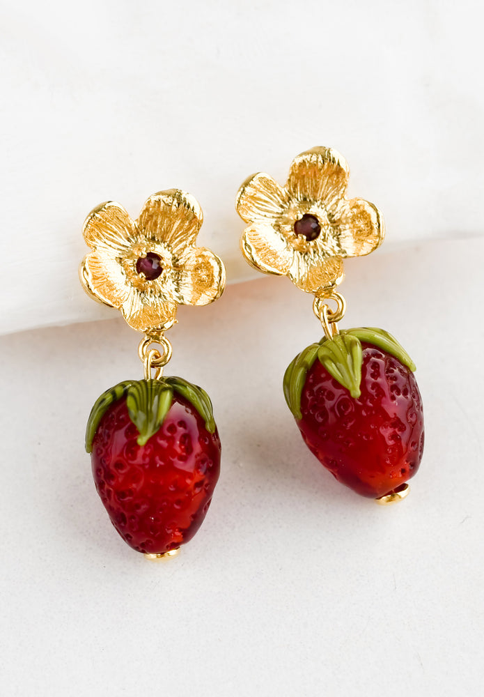 A pair of glass strawberry earrings with floral post.