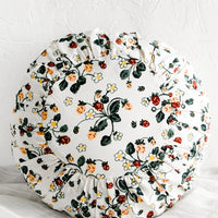 1: A round cushion with pleated detailing in strawberry print.