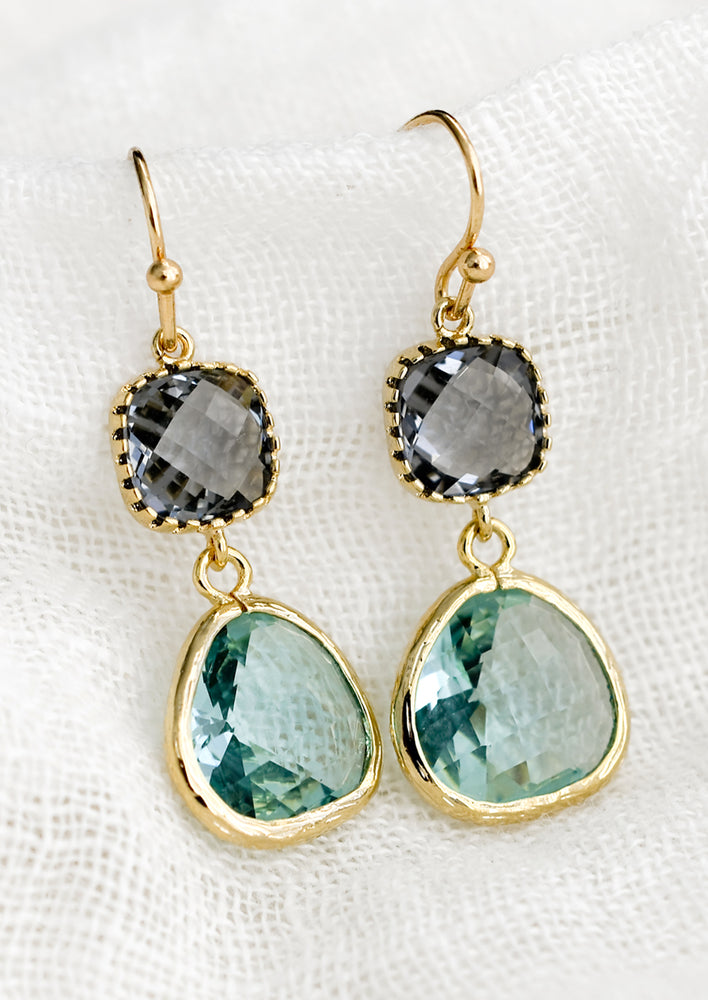 A pair of two-stone bezeled gem earrings in grey and aqua.