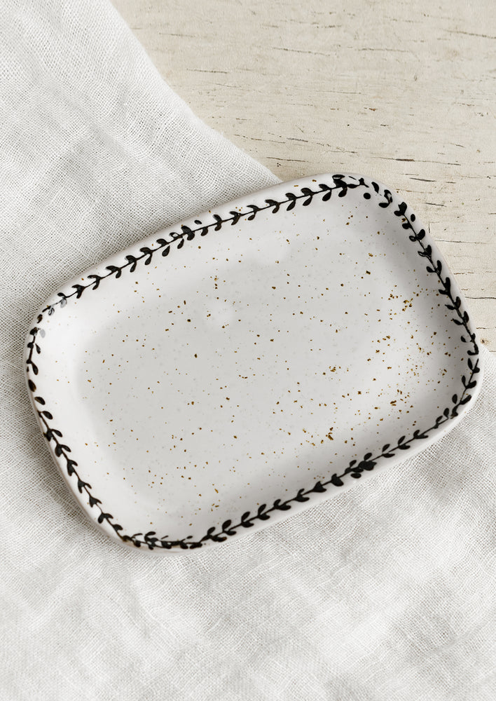 A rounded rectangle tray with black leaf motif border.