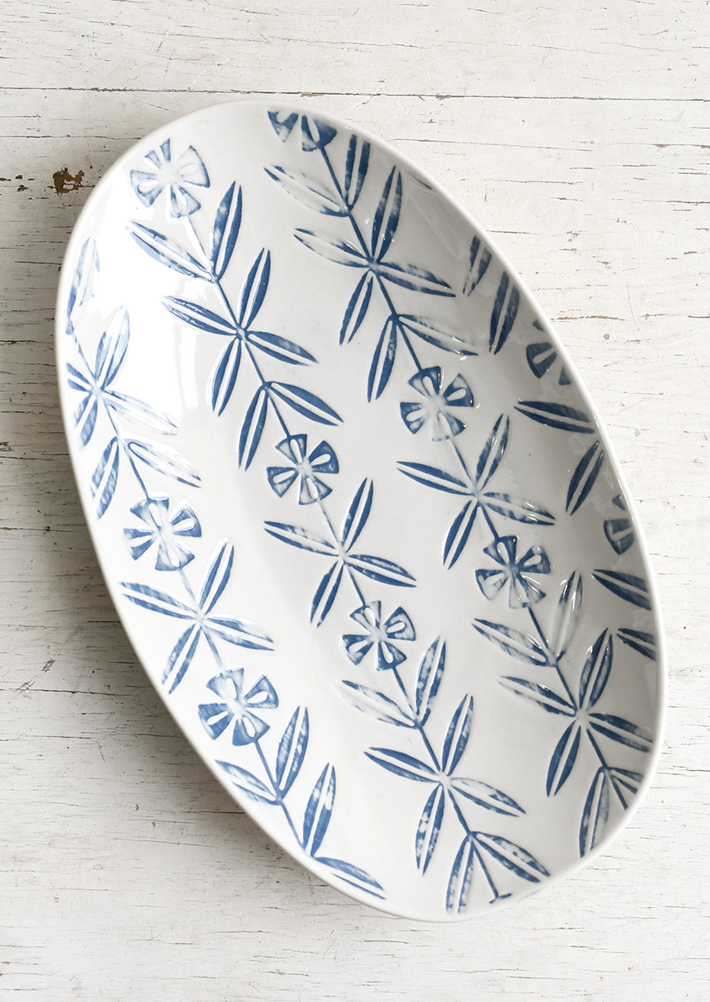 1: An oval shaped ceramic platter with blue imprint design.