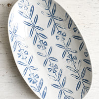 1: An oval shaped ceramic platter with blue imprint design.