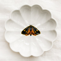 Black Moth: A white ceramic dish with scalloped shape and black and yellow moth illustration at center.