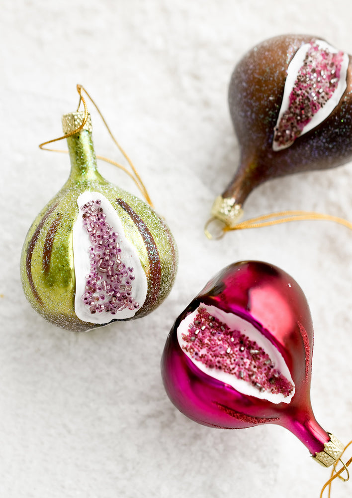 Three glass fig ornaments in green, brown and purple.