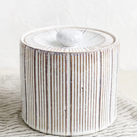 1: A cylindrical lidded ceramic jar in white with contrasting ribbed texture. 