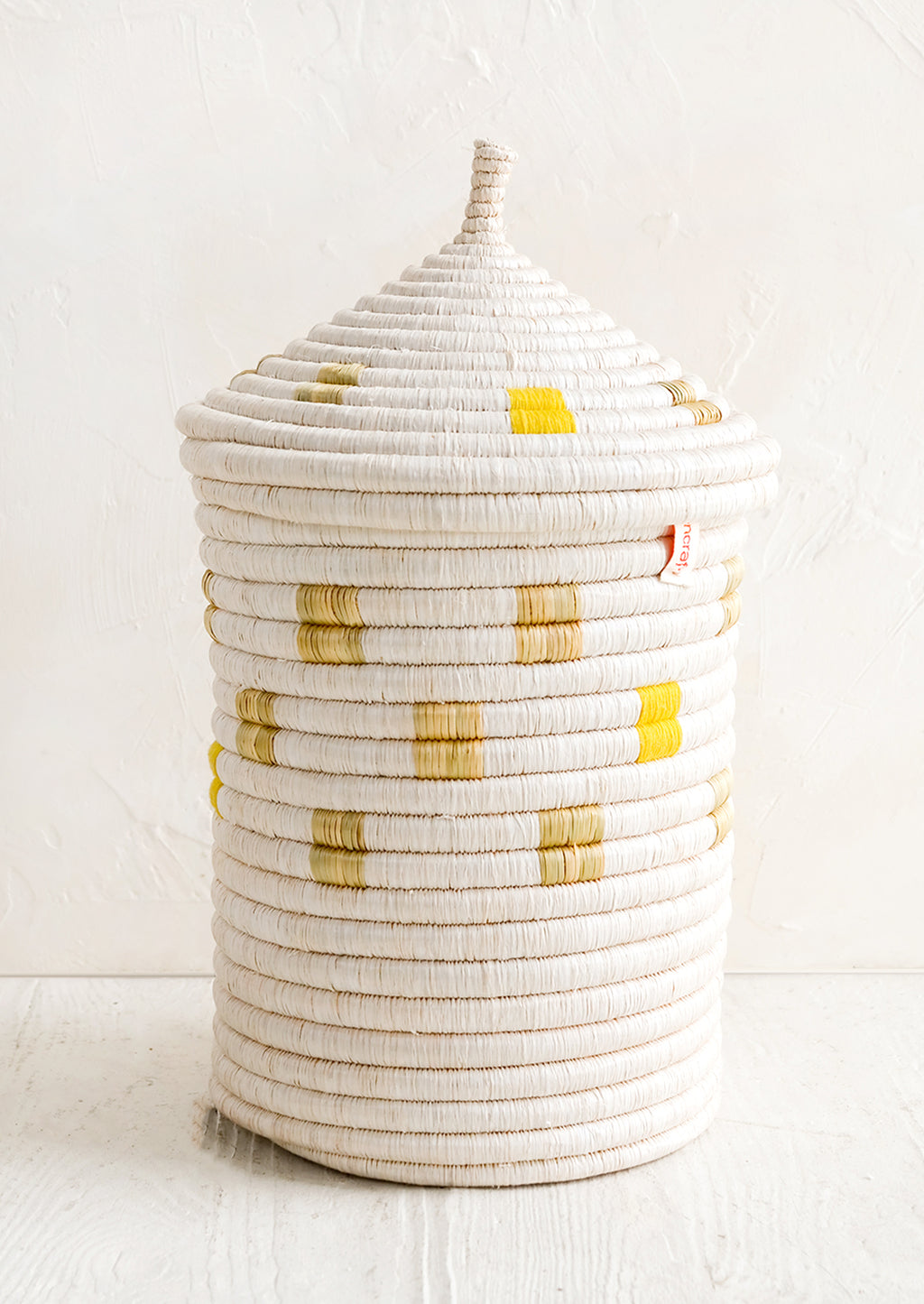 Large [$110.00]: A tall woven basket with gourd-style lid in white with natural and yellow square pattern.