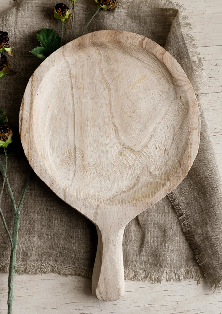 1: A round paddle shaped tray in natural paulownia wood.