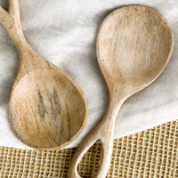 2: A wide paddle shaped spoon in light colored wood with loop handle.
