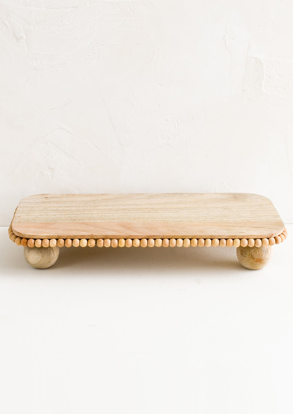 1: A rectangular wooden riser with round feet and beaded detail.