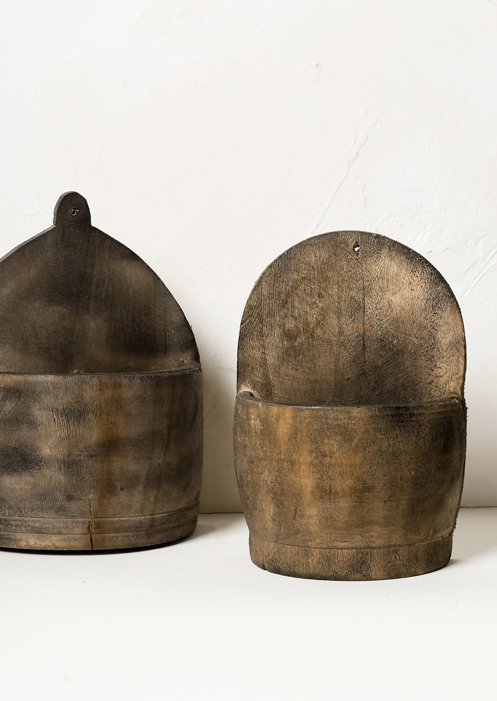 1: Two vintage looking wooden wall baskets in slightly different shapes.