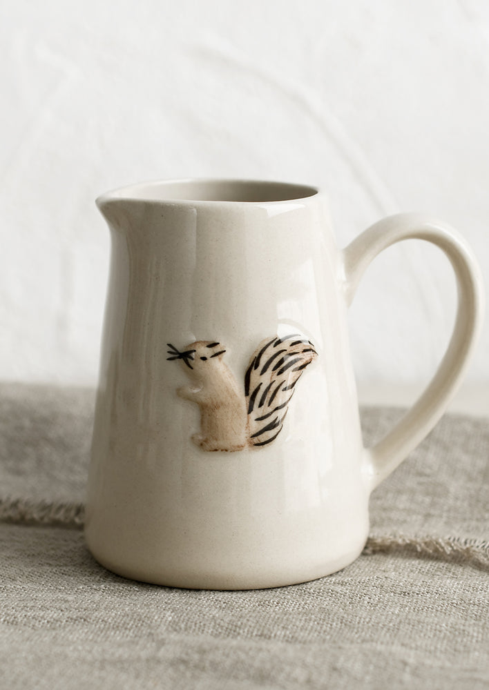 A small creamer pitcher in natural ivory with squirrel motif.