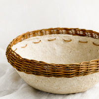 1: A natural paper mache bowl with brown wicker trim at top.