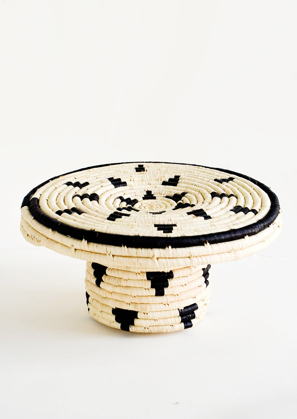 1: Round woven raffia cake stand in natural with black triangle print
