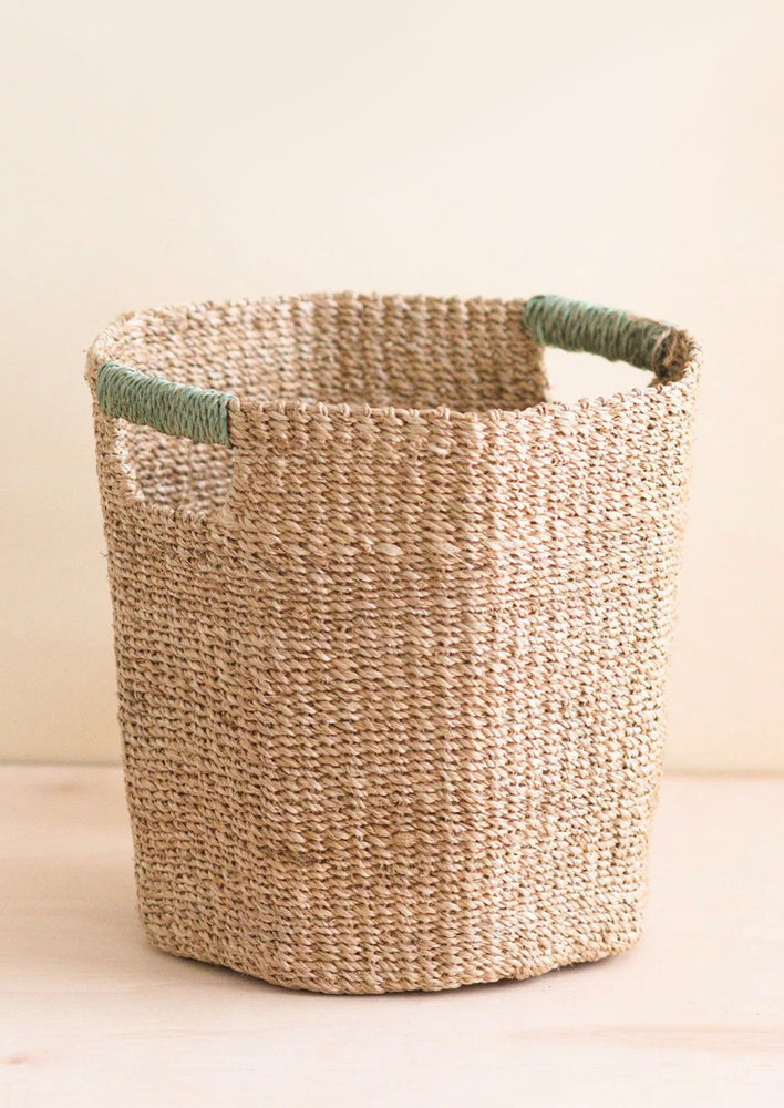 An octogonal natural basket wageith s wrapped cutout handle.