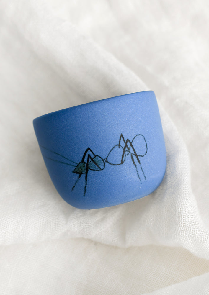 An extra small cornflower blue porcelain cup with ant sketch.